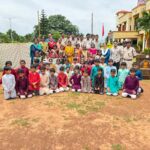 Large group of indian schoolchildren in colorful outfits posing with teachers and police officers outdoors at a campus